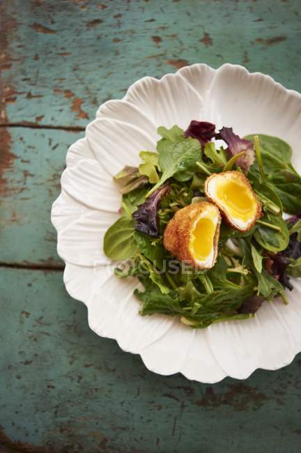 Top view of fried poached egg over mixed greens — Stock Photo