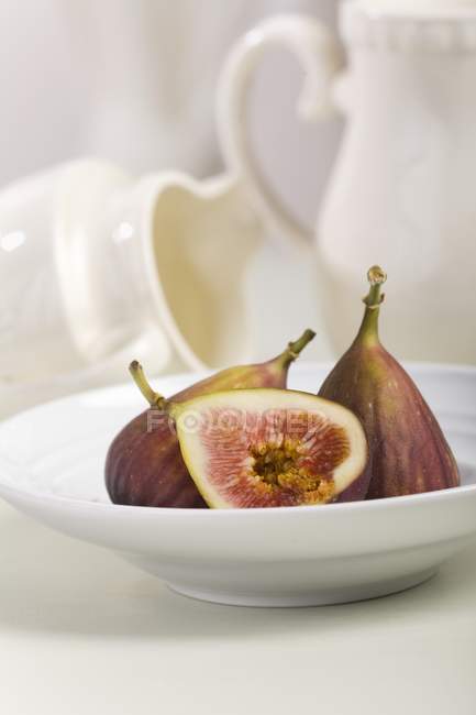 Half and whole figs in white bowl — Stock Photo