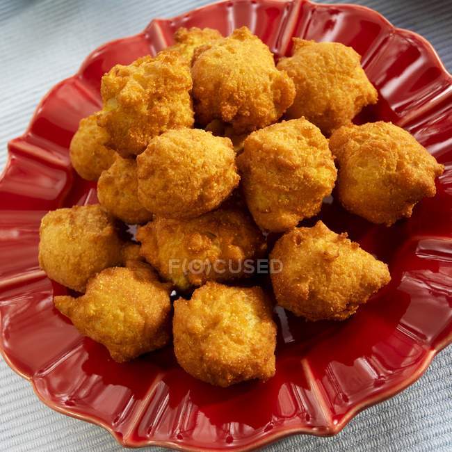 Closeup tilted view of Hush Puppies on a red plate — Stock Photo