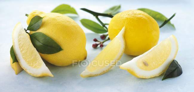 Cuñas de limón y hojas de limón - foto de stock