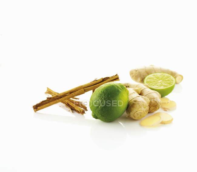 Limes with ginger and cinnamon sticks — Stock Photo