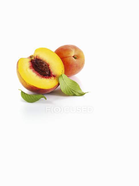 Половина персика и абрикоса с листьями — стоковое фото