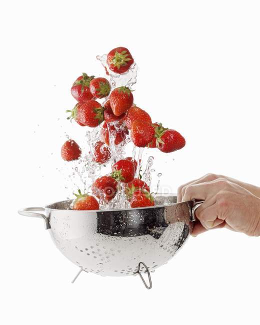 Femme laver les fraises dans une passoire — Photo de stock