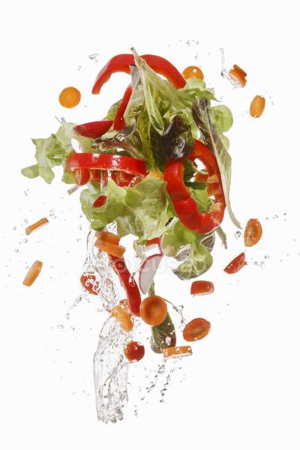 Salad ingredients being washed on white background — Stock Photo