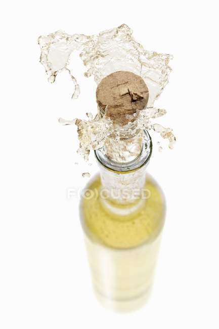 Vino bianco spruzzando fuori dalla bottiglia — Foto stock