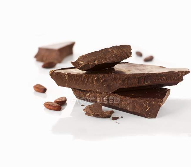 Schokoladenstücke und Kakaobohnen — Stockfoto