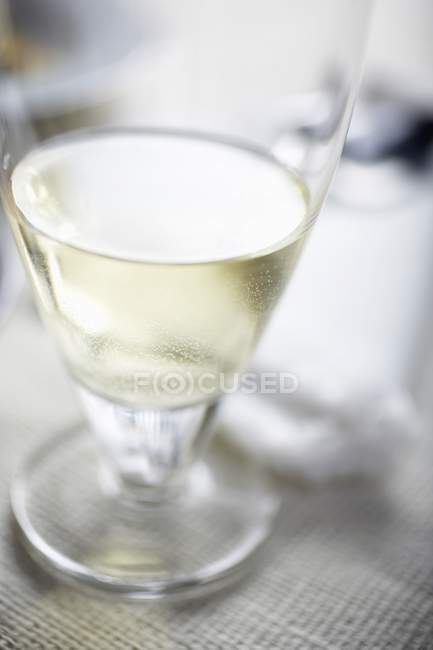 Copa de vino blanco en la mesa - foto de stock