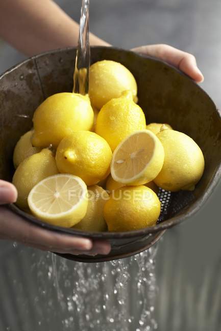 Manos sosteniendo colador con limones - foto de stock