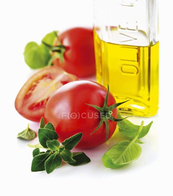 Tomatoes and bottle of olive oil — Stock Photo