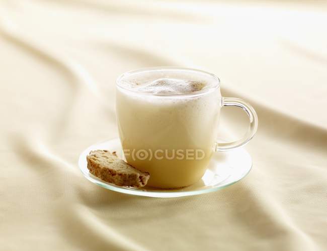 Vue rapprochée du lait de poule épicé dans une tasse en verre avec Biscotti — Photo de stock
