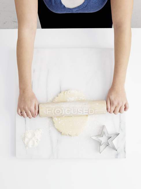 Vista superior da mulher rolando para fora da pastelaria em uma superfície de trabalho de mármore — Fotografia de Stock