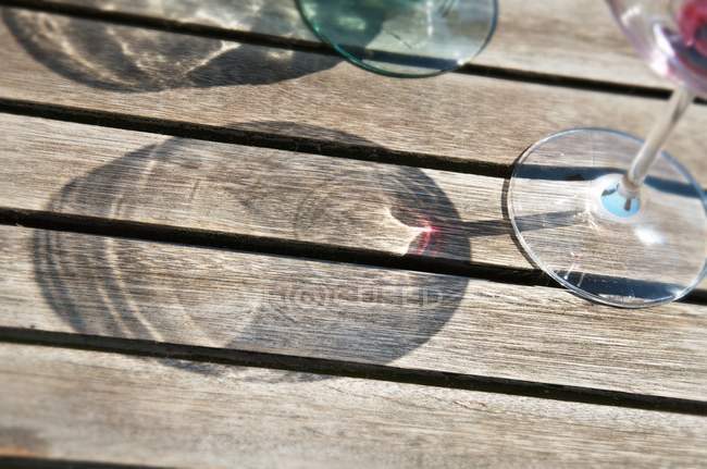 Vista de primer plano de las sombras de las copas de vino sobre una superficie de madera - foto de stock