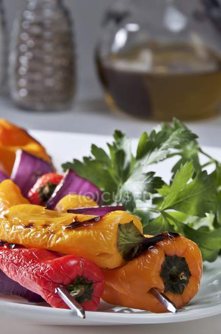 Grilled peppers with herbs on white plate — Stock Photo