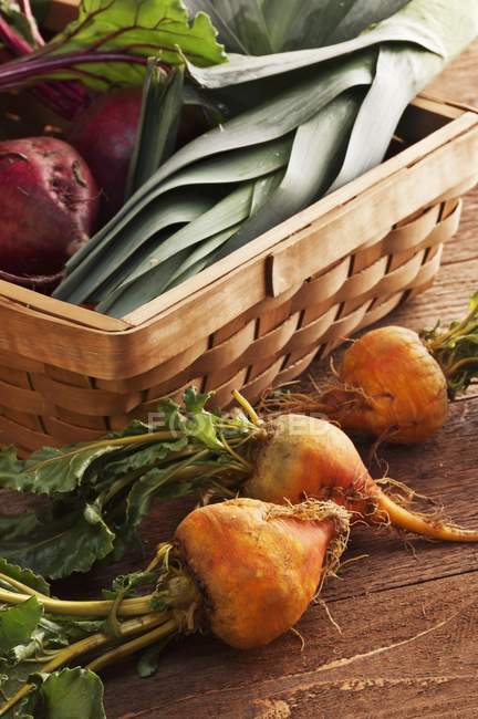 Organic Golden Beets Next to a Basket Filled with Red Beets and Leeks — Stock Photo