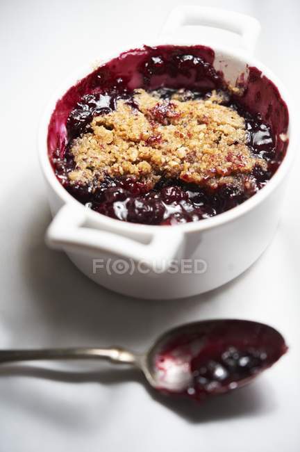 Closeup view of mixed berry crumble in baking dish with spoon — Stock Photo