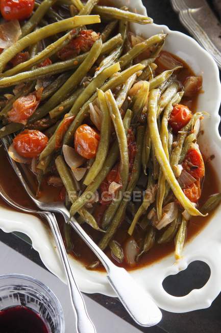 Фасоль и томатный салат в белом блюде с ложкой — стоковое фото