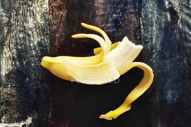Banane demi-pelée mordue — Photo de stock
