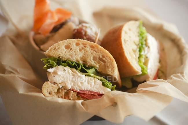 Sandwichs à la mozzarella, aux tomates et à la romaine sur Ciabatta dans un panier doublé en papier — Photo de stock