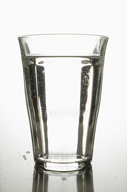 Vaso de agua en la mesa - foto de stock
