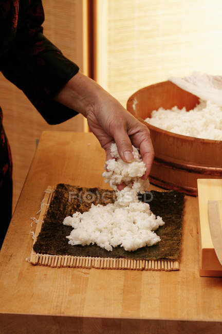 Женщина кладет рис на нори — стоковое фото