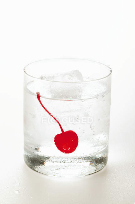 Drink with ice cubes and cocktail cherry — Stock Photo