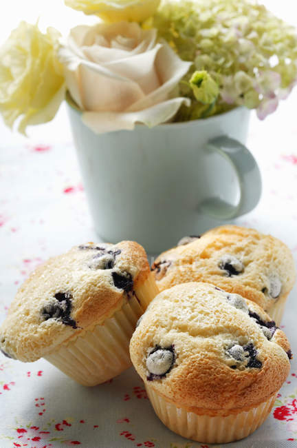 Muffins with cup of flowers — Stock Photo