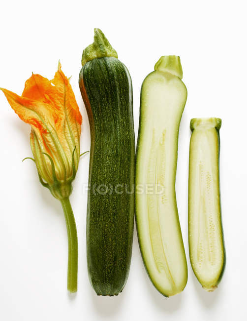 Whole and half courgettes with flower — Stock Photo