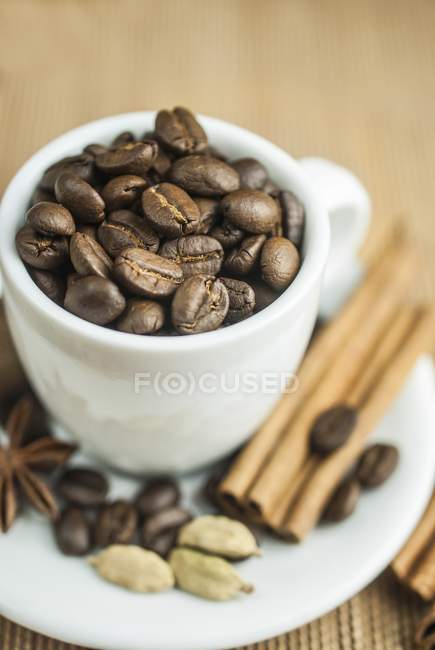 Granos de café en taza con especias - foto de stock