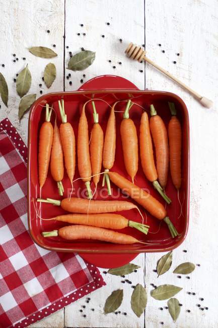 Zanahorias en plato rojo para hornear - foto de stock
