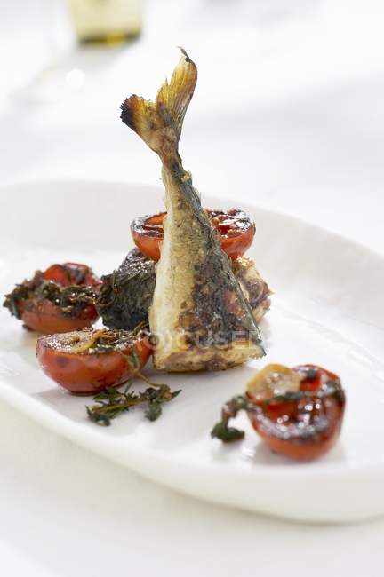 Fried herring with tomatoes  on white plate — Stock Photo
