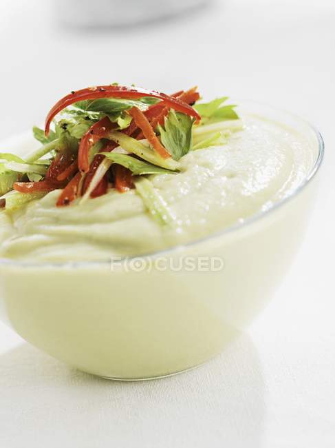A dip with cucumber, red pepper and coriander on white surface — Stock Photo