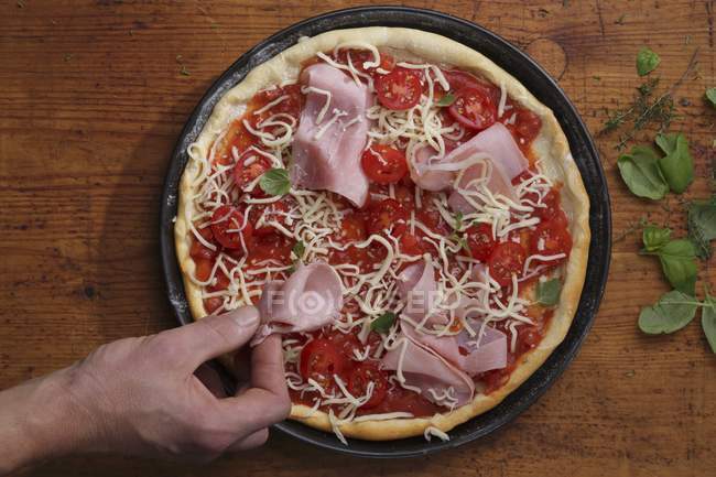 Topping a pizza with ham — Stock Photo