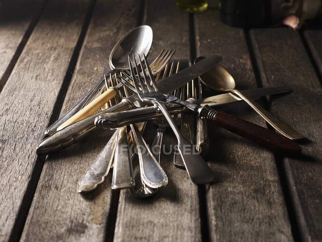 Closeup view of old silver cutlery heap on wooden planks — Stock Photo