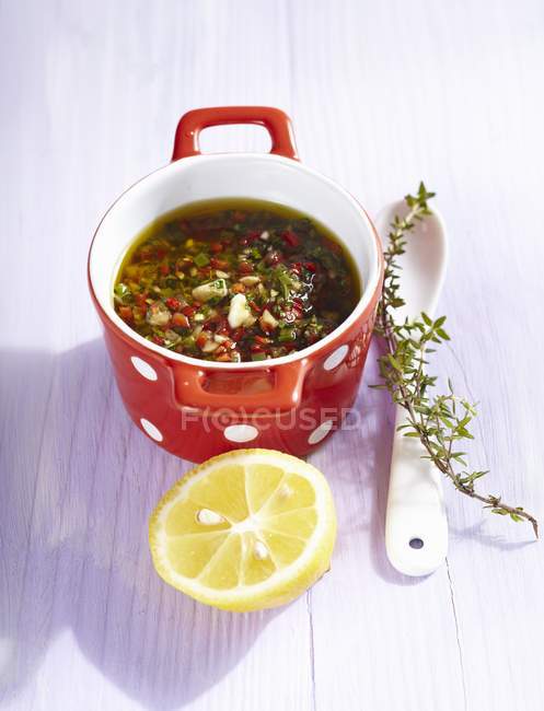 Elevated view of pepper dressing with herbs and lemon half — Stock Photo