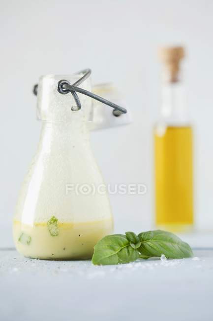 Vista de cerca de aderezo de ensalada de albahaca cremosa en botella - foto de stock