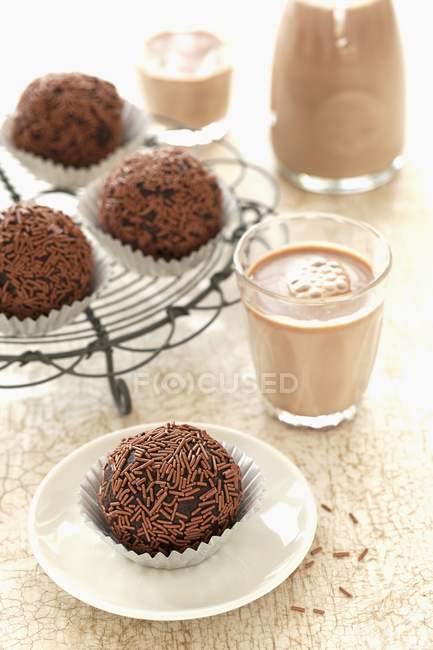 Closeup view of chocolate nut truffles and glasses of cocoa — Stock Photo
