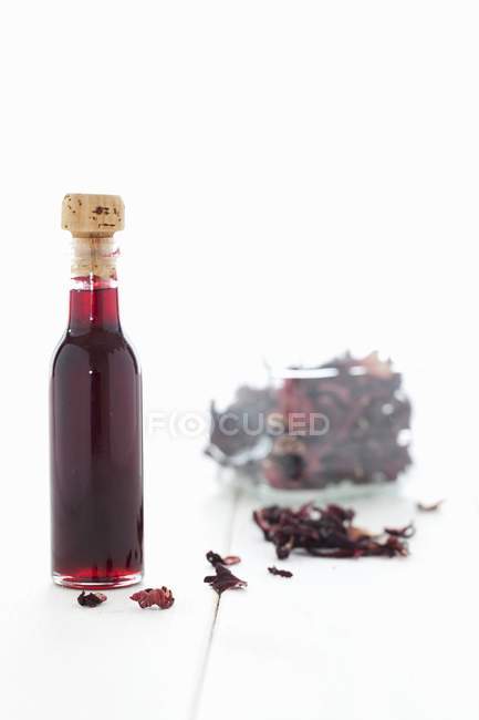 Vista de perto de uma garrafa de um copo de xarope de hibisco e flores secas de hibisco — Fotografia de Stock