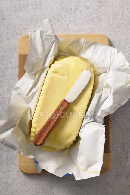 Vista superior de la mantequilla en un pedazo de papel con un cuchillo de mantequilla - foto de stock
