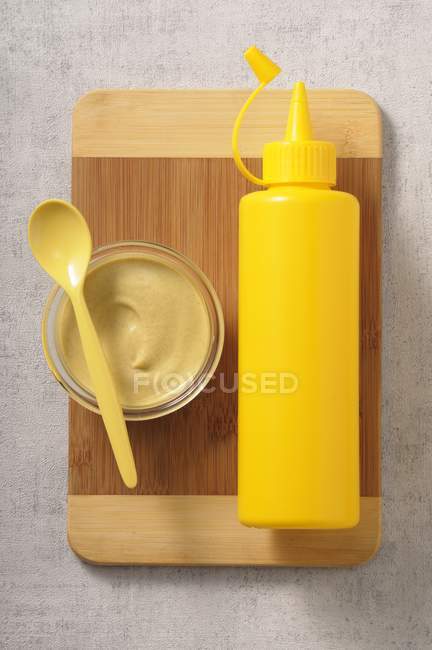 Mustard in glass bowl with plastic bottle — Stock Photo