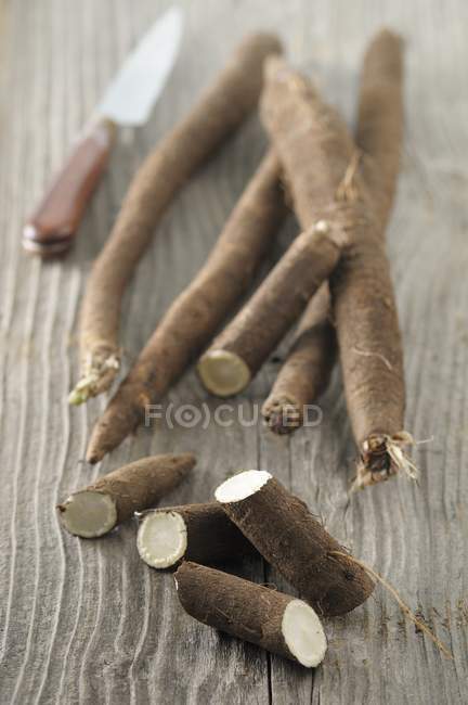 Black salsify, partially sliced, on a wooden surface — Stock Photo