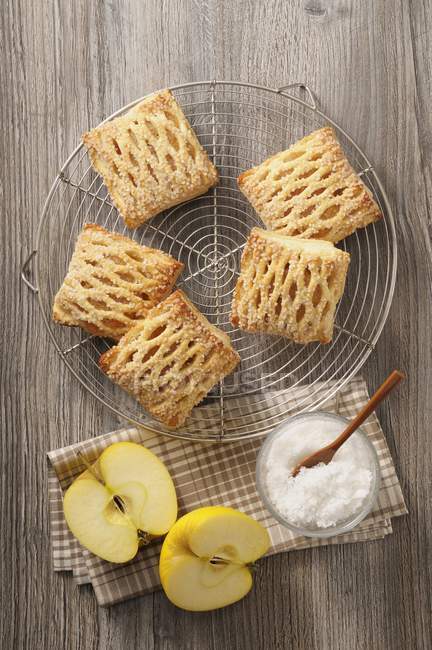 Vue de dessus des pâtisseries aux pommes avec sucre sur support métallique et surface en bois — Photo de stock