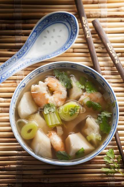 Prawn soup with leek in bowl over straw mat with chopsticks — Stock Photo