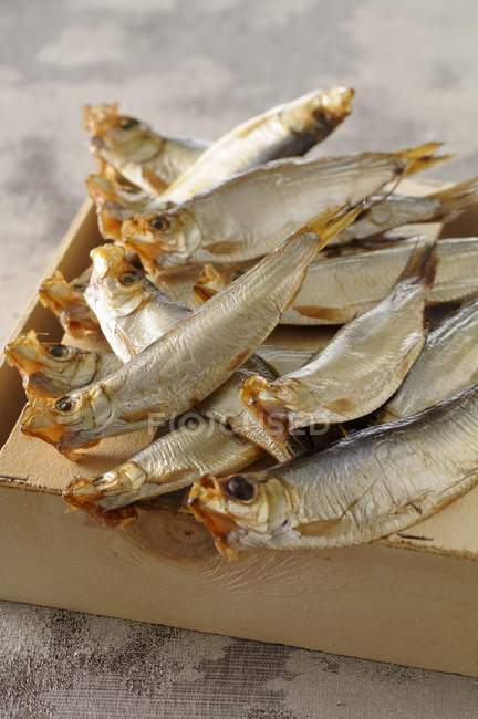 Smoked sprats on wooden crate — Stock Photo