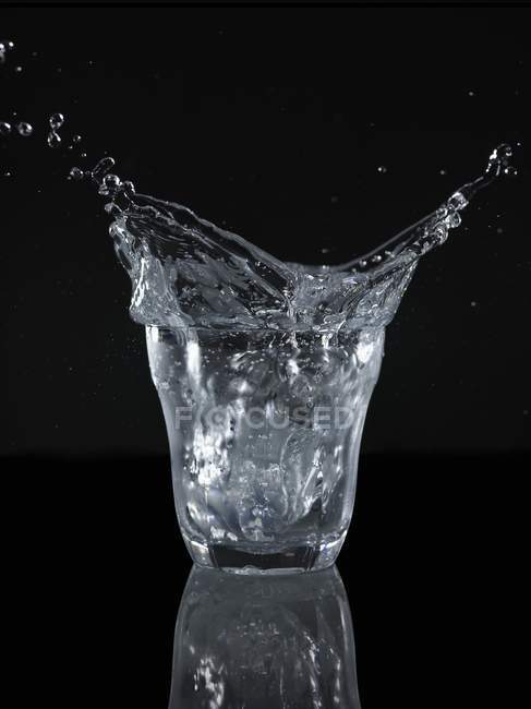 Salpicaduras de agua de un vaso - foto de stock