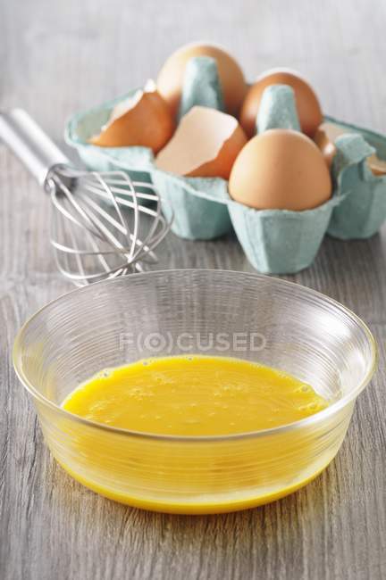 Egg yolks, eggs and whisk — Stock Photo