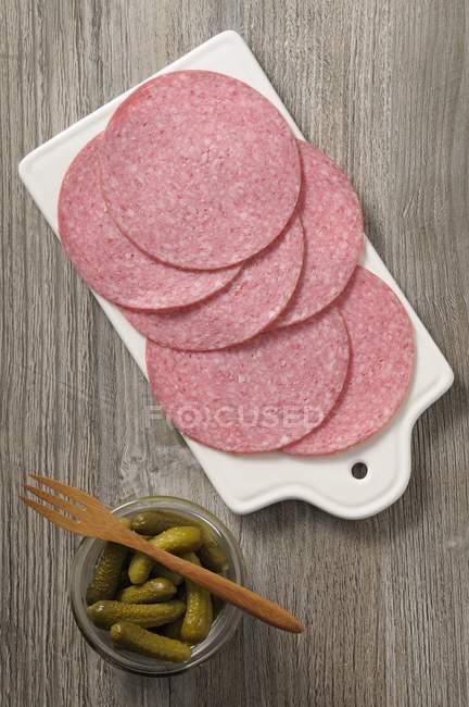 Salami slices and jar of gherkins — Stock Photo