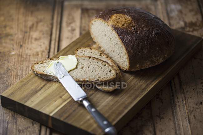 Pão fatiado com manteiga e faca — Fotografia de Stock