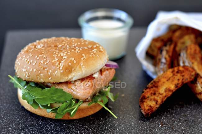 Salmon burger with potato wedges — Stock Photo