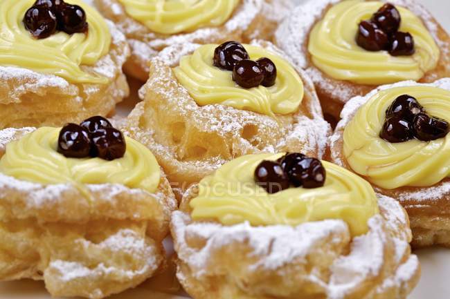 Vista de cerca de Zeppole di San Giuseppe choux pasteles con crema y cerezas - foto de stock