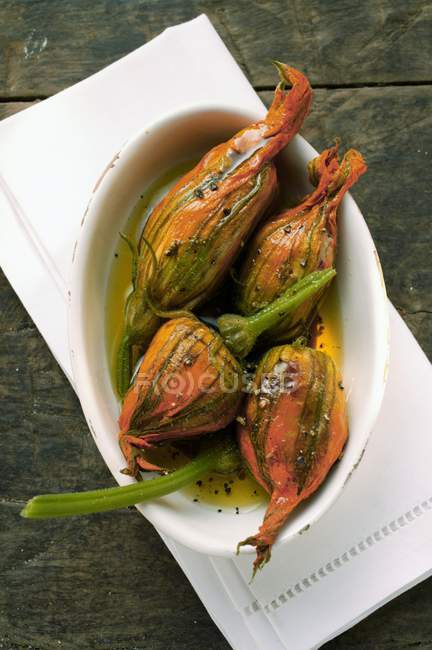 Marinated stuffed courgette flowers in white dish — Stock Photo